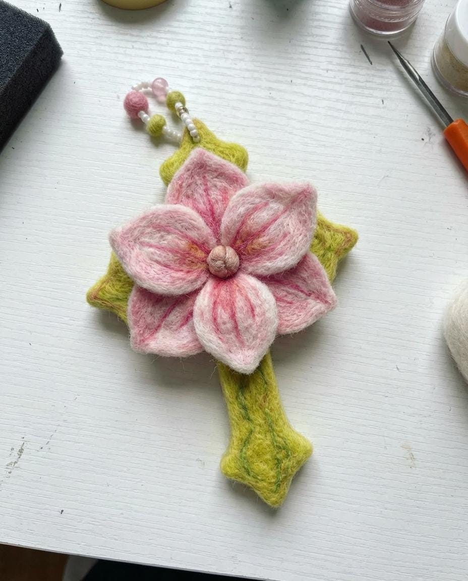 Hand felted wool floral cross pendant by Jiajia Felt Studio, showcasing detailed felt jewelry with colorful floral design.