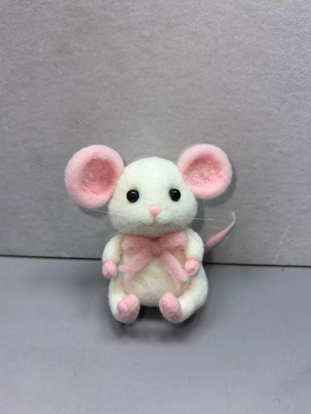 Needle felted white mouse with pink ears and a pink bow, sitting