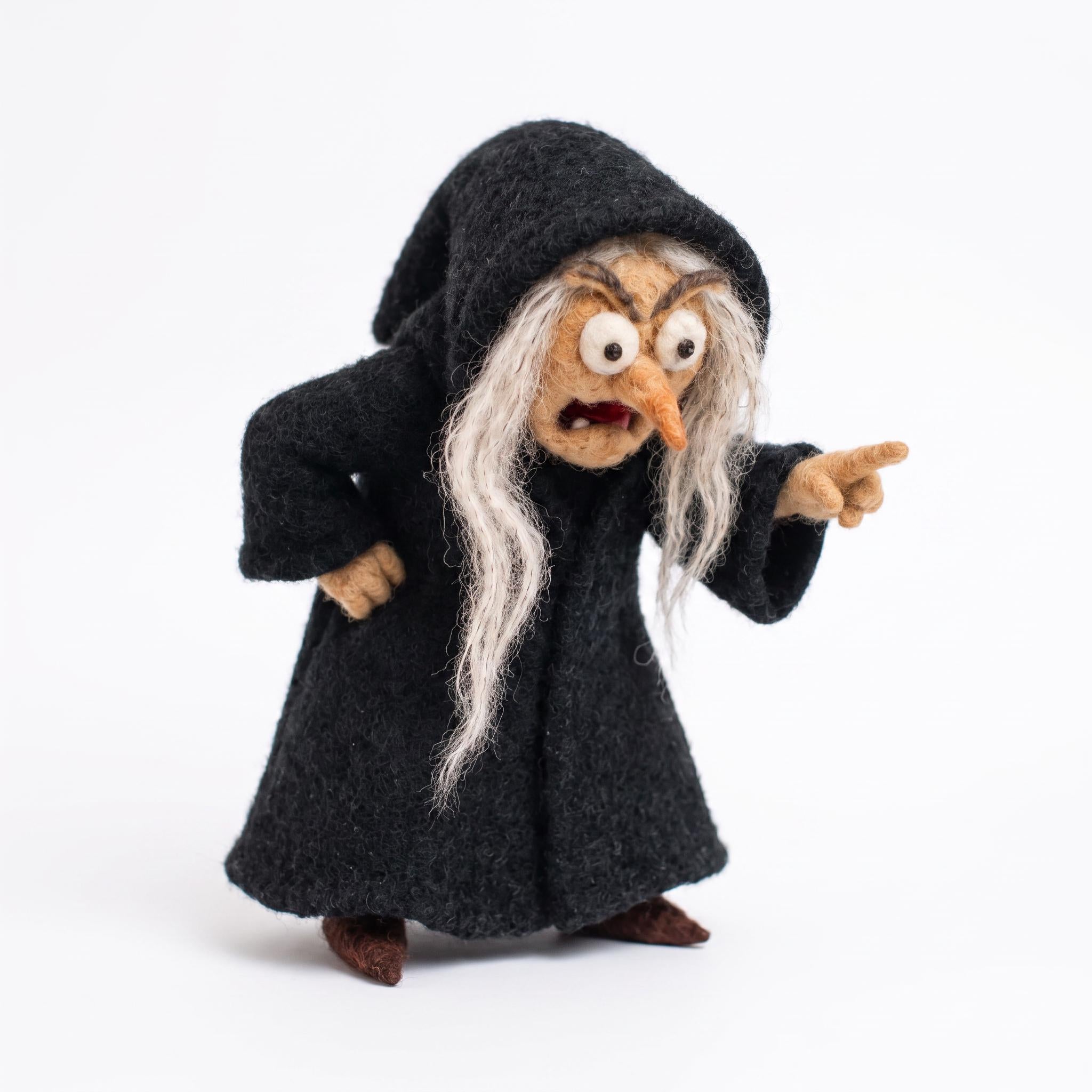 Needle felted witch figurine in black hooded cloak, pointing finger
